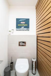 uma casa de banho com um WC branco e uma parede de madeira em Apartmán Praha Žižkov - DZ RENT em Praga