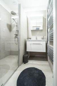 uma casa de banho com um chuveiro, um lavatório e um espelho. em Apartmán Praha Žižkov - DZ RENT em Praga