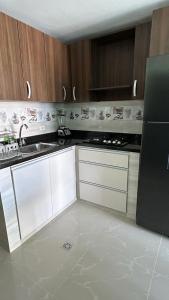 cocina con armarios blancos y nevera negra en Apartamento Amoblado Barranquilla San Jose, en Barranquilla