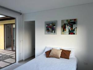 ein Schlafzimmer mit einem weißen Bett mit zwei Bildern an der Wand in der Unterkunft Hermosa y Moderna Casa Campestre in La Mesa