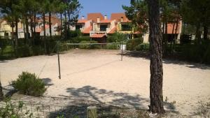 a volleyball court with a tree in the middle at Buganvilias House in Praia de Mira