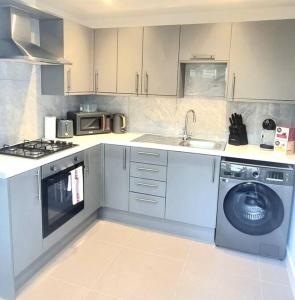 a kitchen with a sink and a washing machine at Watford Gem Private Garden Mins to Harry Potter Studio in Watford