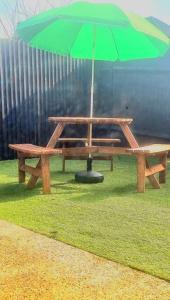 una mesa de picnic con una sombrilla verde en la hierba en Watford Gem Private Garden Mins to Harry Potter Studio en Watford