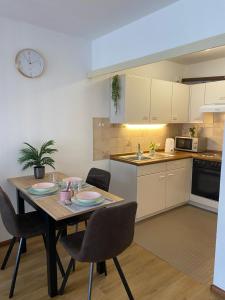 une cuisine avec une table, des chaises et une horloge murale dans l'établissement Appartement Au Rhin mit Balkon in Bad Bellingen, à Bad Bellingen
