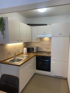 a kitchen with white cabinets and a sink and a microwave at Appartement Au Rhin mit Balkon in Bad Bellingen in Bad Bellingen
