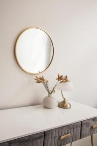 a mirror on a white wall above a vanity with a vase at Cityscape 2-BR - Leicester's Premier Urban Retreat in Leicester