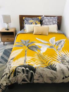 Una cama con una manta amarilla con palmeras. en CHILL HOME- T2 Aménagé, en Sainte-Suzanne