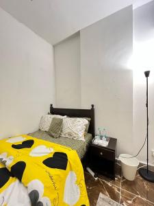 a bedroom with a bed with a yellow blanket at Tanih's Lodging in Abu Dhabi