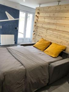 Un dormitorio con una cama grande con dos almohadas amarillas. en Rez de jardin Cosy entre Disney et Paris, en Lagny