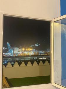 een raam met uitzicht op de stad 's nachts bij apartment a ksar sghir in front Tanger Med ferry port in Agaouz