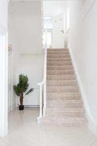 a staircase in a white room with a plant at Stunning Large 4 Bedroom Victorian Home London in London
