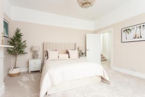 a white bedroom with a white bed and a potted tree at Stunning Large 4 Bedroom Victorian Home London in London