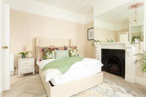 a white bedroom with a bed and a fireplace at Stunning Large 4 Bedroom Victorian Home London in London