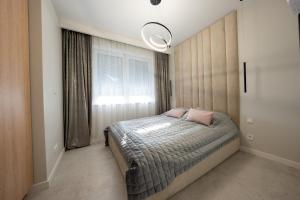 a bedroom with a bed with pink pillows on it at Apartament z Tarasem Morska 6 Rewal 50m do morza in Rewal