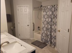 a bathroom with a shower with a sink and a tub at Bedroom Four minutes from beach in Pensacola