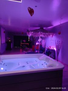 - une grande baignoire blanche dans une chambre avec éclairage violet dans l'établissement Le relax, à La Louvière