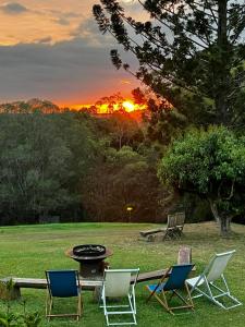 a group of chairs and a table in a field with the sunset at Noosa Hinterland Escape in Black Mountain