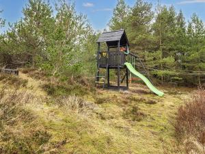 um parque infantil num campo com escorrega em Holiday home Rømø XV em Bolilmark