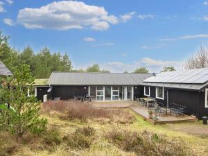 una casa negra con porche y terraza en Holiday home Rømø XV, en Bolilmark