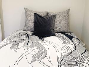 a bed with a black and white comforter and a pillow at Holiday home Stubbekøbing IV in Stubbekøbing