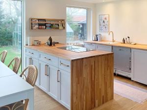a kitchen with white cabinets and a wooden island at Holiday home Stubbekøbing IV in Stubbekøbing