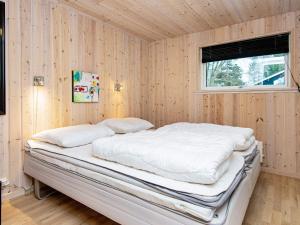 a bed in a room with wooden walls and a window at Three-Bedroom Holiday home in Silkeborg 3 in Dalsgårde