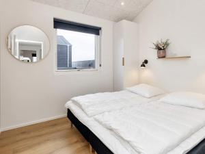 a white bedroom with a large bed and a mirror at 5 star holiday home in Løkken-By Traum in Løkken