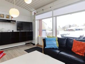 a living room with a black leather couch and a tv at 6 person holiday home on a holiday park in Sæby in Sæby