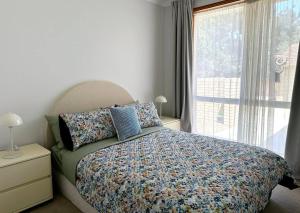 - une chambre avec un lit doté d'oreillers et d'une fenêtre dans l'établissement 3 Bedroom Holiday Townhouse @ Belconnen, à Belconnen