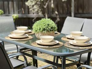 une table avec des assiettes et des tasses et une plante en pot dans l'établissement 3 Bedroom Holiday Townhouse @ Belconnen, à Belconnen