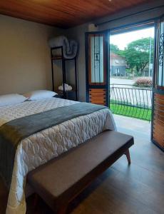1 dormitorio con cama y ventana grande en Pousada Bégamo - Vale dos vinhedos, en Bento Gonçalves