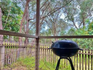 a grill sitting on a stand in front of a fence at A Lovely Pool House in Forest in Wonga Park
