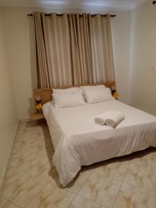 - une chambre avec un lit blanc et 2 serviettes dans l'établissement Zen in Ibanda, à Kitwe