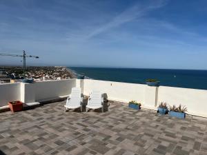 2 Stühle und ein Tisch auf einer Terrasse mit Meerblick in der Unterkunft Ático El Faro Cullera in Faro de Cullera