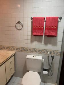 uma casa de banho com um WC branco e toalhas vermelhas em Pituba sol flat em Salvador