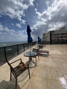uma mesa e cadeiras e um guarda-sol no telhado em Pituba sol flat em Salvador