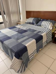 uma cama com um cobertor azul e branco em Pituba sol flat em Salvador