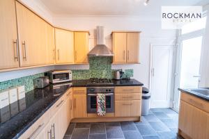 a kitchen with wooden cabinets and a stove top oven at Northumberland House 5 Bed Apartment Close To Beach with Parking by RockmanStays in Southend-on-Sea
