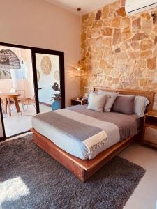 a bedroom with a bed with a stone wall at Veranera in Uvita