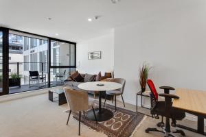 a living room with a couch and a table and chairs at The CityScape Apartment with Wi-Fi and Balcony in Auckland