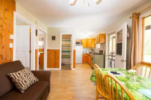 Il dispose d'une cuisine et d'un salon avec une table et un canapé. dans l'établissement Fiddler's Green Country Cottages, à Brackley Beach