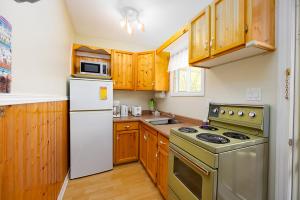 une cuisine avec des armoires en bois et un réfrigérateur blanc dans l'établissement Fiddler's Green Country Cottages, à Brackley Beach 15 autres photos