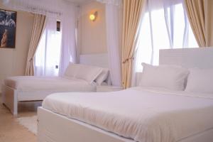 1 dormitorio blanco con 2 camas y ventana en RIMA 3BRM Cozy Apartment en Kampala