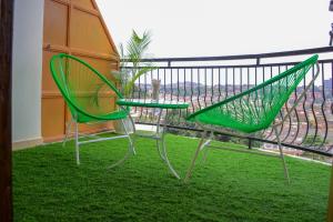 2 sillas verdes y una mesa en el balcón en RIMA 3BRM Cozy Apartment en Kampala