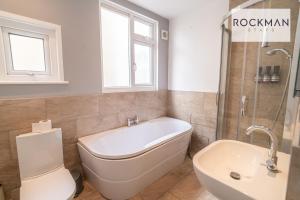 uma casa de banho com uma banheira, um WC e um lavatório. em Northumberland House 5 Bed Apartment Close To Beach with Parking by RockmanStays em Southend-on-Sea