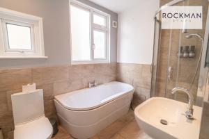 a bathroom with a tub and a toilet and a sink at Northumberland House 5 Bed Apartment Close To Beach with Parking by RockmanStays in Southend-on-Sea