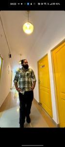 un hombre parado en un pasillo con una puerta amarilla en Yellow Inn Guest House, en Lucknow