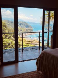a bedroom with a view of the ocean from a balcony at Tinamaste in Uvita