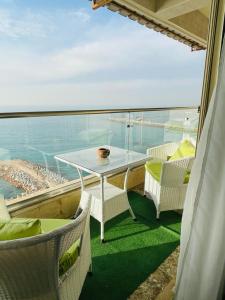 balcón con mesa, sillas y vistas al océano en Alexander House, en Alejandría