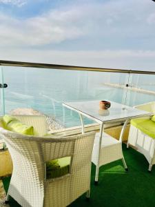 una mesa y sillas en un balcón con vistas al océano en Alexander House, en Alejandría
